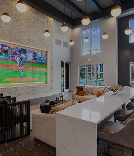The resident lounge at Alta Avondale Apartments in Avondale, AZ, featuring couches and a multi-panel TV.